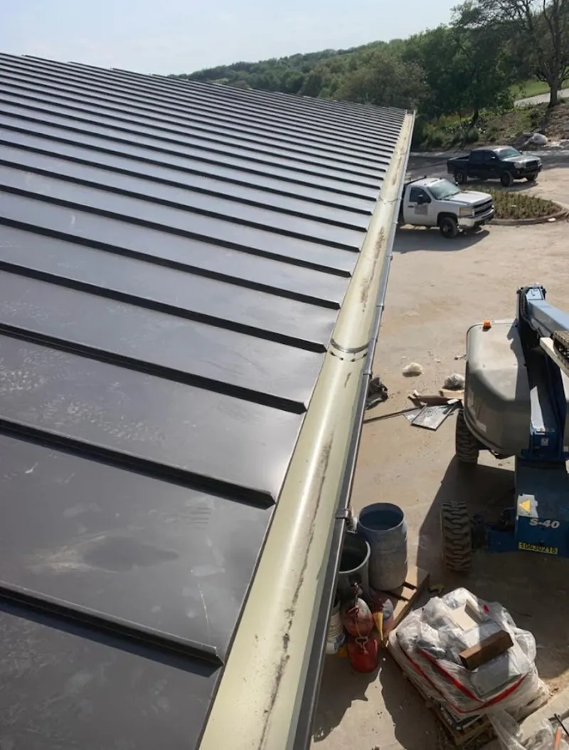 Standing seam panel and gutter detail on a metal roofing jobsite in Fenton